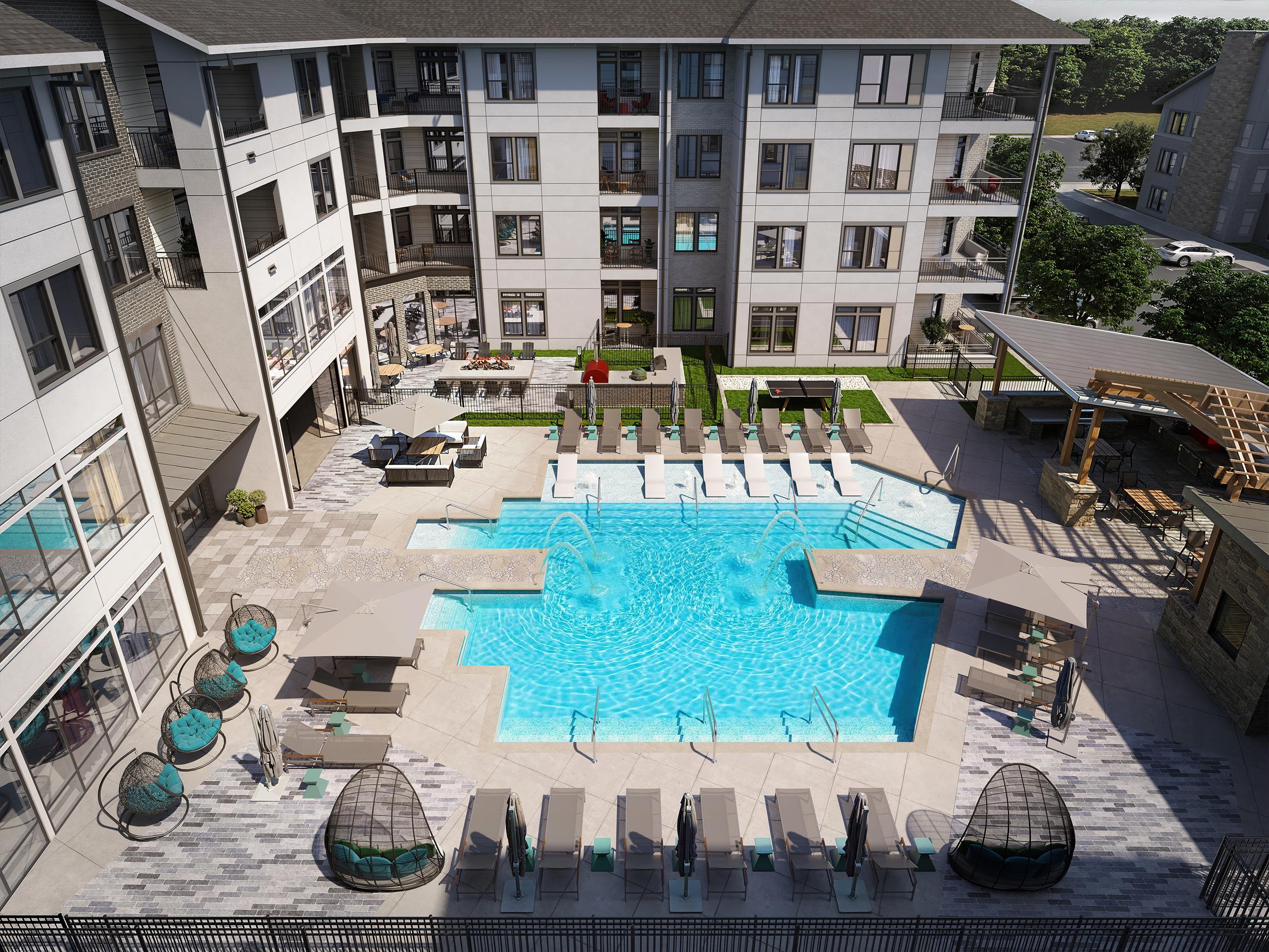 A large swimming pool surrounded by sun loungers and umbrellas in front of a multi-story apartment building.